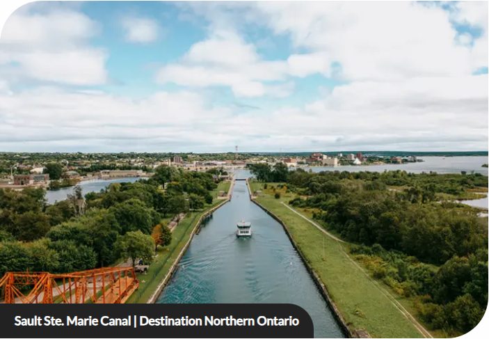 A boat travelling along the Sault Ste. Marie Canal toward the waterfront